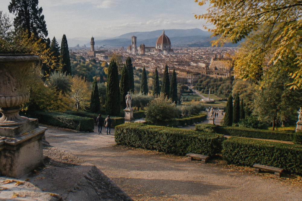 Looking down from the amphitheatre terrace over clipped green hedges and cypress avenues in the Boboli Gardens, dry gravel paths, scattered yellow leaves