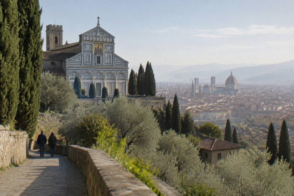 High on a cypress and olive wooded hillside, the abbey's striped green-and-white marble facade catching sun while the hazy city of terracotta rooftops spreads down toward the Arno
