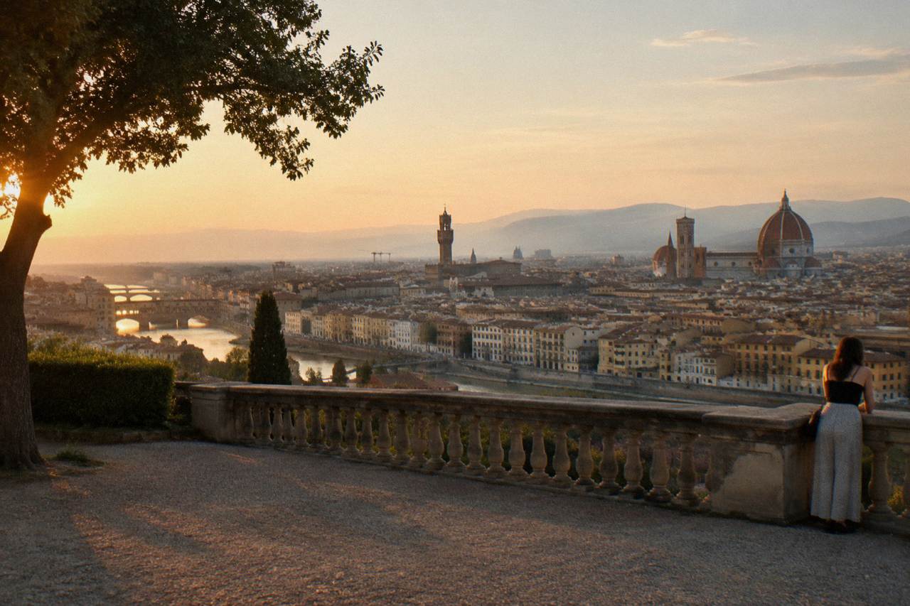 From the high stone terrace above the Arno, jumbled terracotta rooftops and Brunelleschi's great dome in warm haze, dry gravel swept against the balustrade