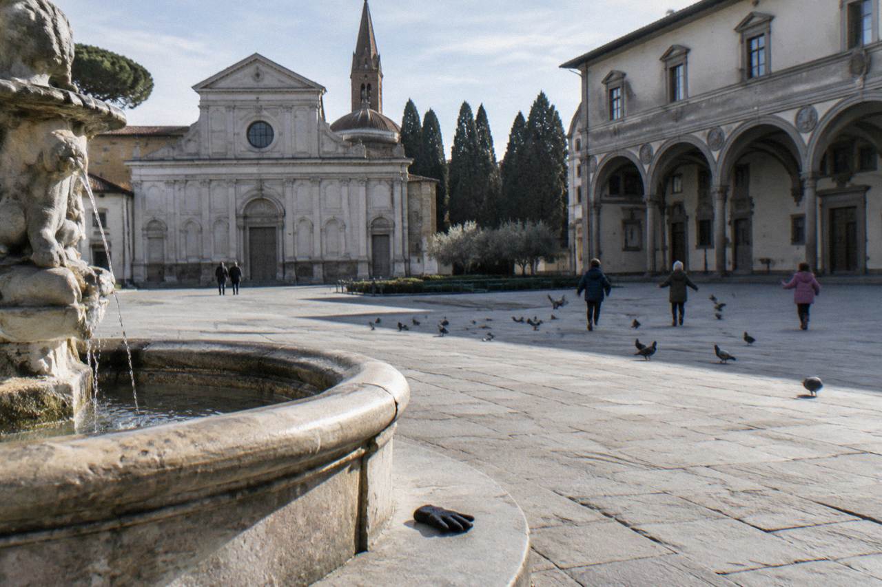 Across the wide square ringed by grey pietra serena arcades, children chasing pigeons far off across the pale flagstones, a dropped glove beside a fountain