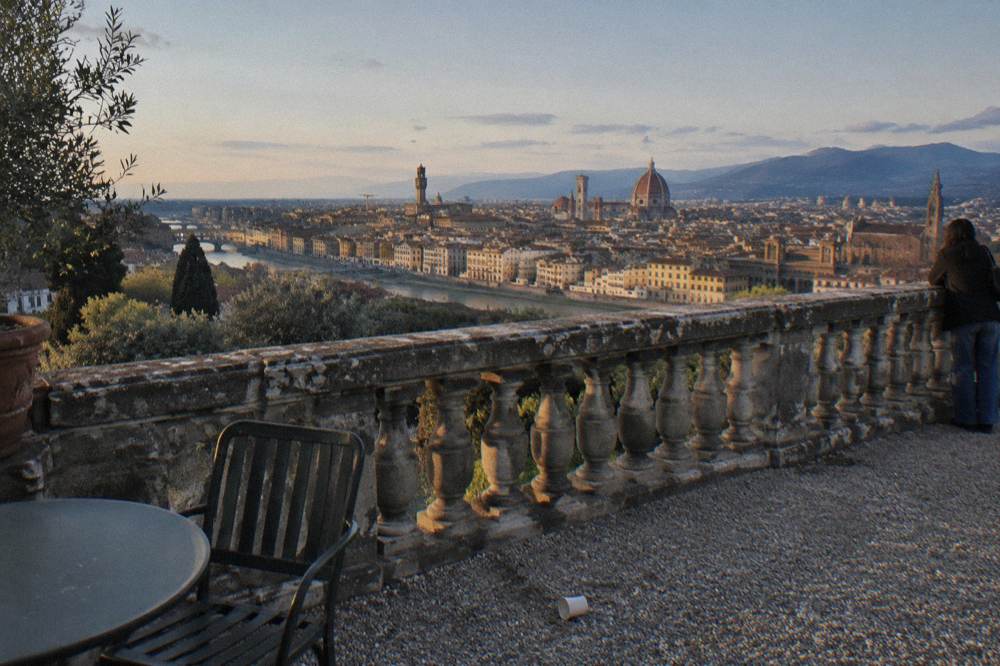 Clear early spring evening on the hillside terrace above Florence, Italy, a weathered stone balustrade in the foreground, terracotta rooftops and the Arno far below