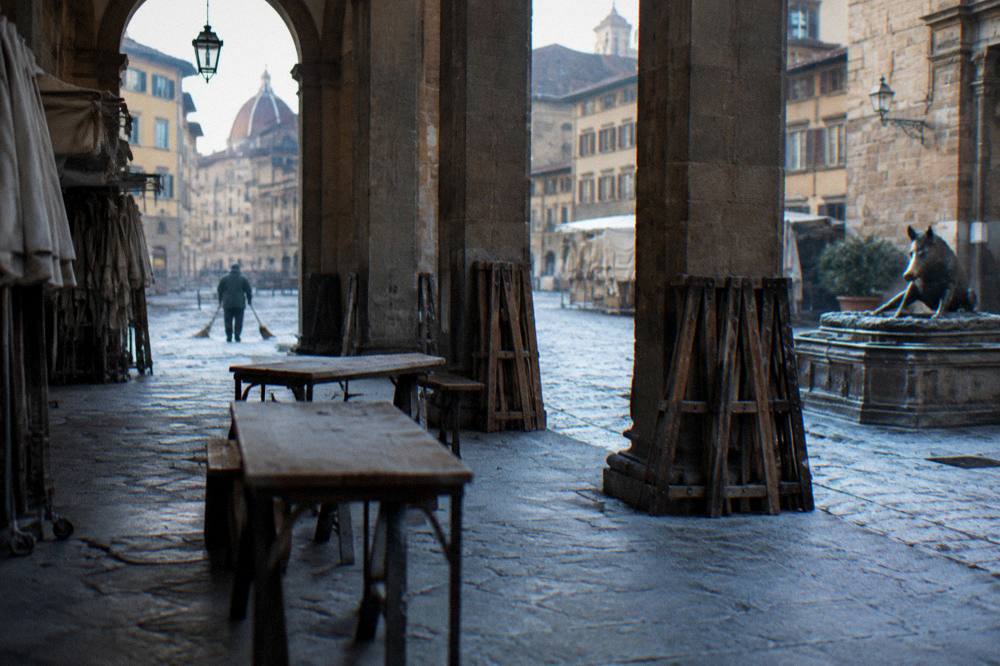 The empty stone loggia of the Porcellino market before stalls open, bare wooden benches and folded trestles along the pietra forte piers, frost on the flagstones