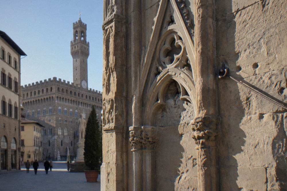 Weathered gothic tracery and pitted stone, a strand of old wire anchored into the masonry, Orsanmichele
